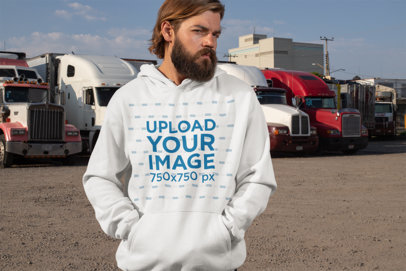 Pullover Hoodie Mockup of a Man Posing with Trucks in the Background