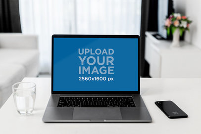 Mockup of a MacBook Pro Placed by a Glass of Water and an iPhone