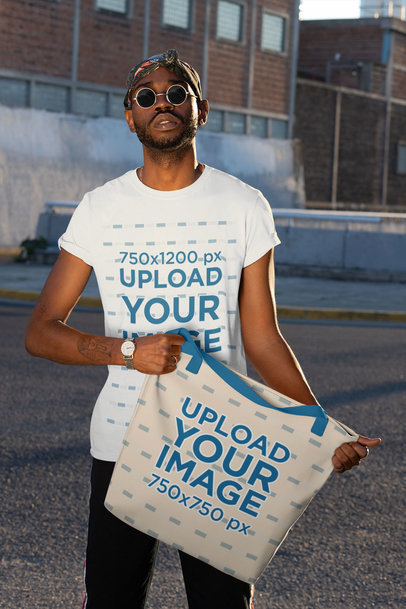 T-Shirt Mockup of a Man Holding a Tote Bag with Customizable Strap