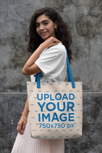 Tote Bag Mockup of a Woman in Front of a Concrete Wall