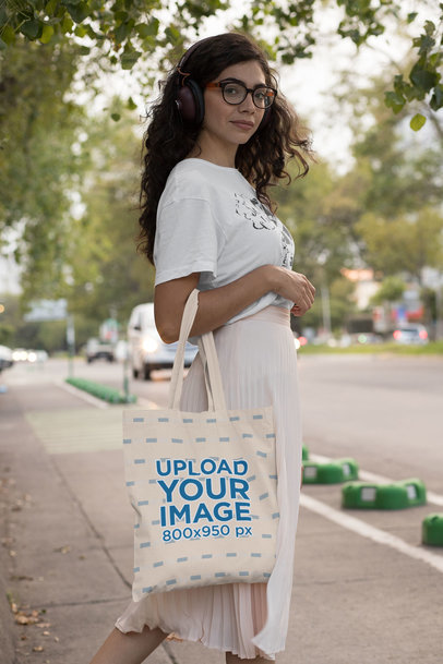 Tote Bag Mockup of a Woman with Headphones on the Street