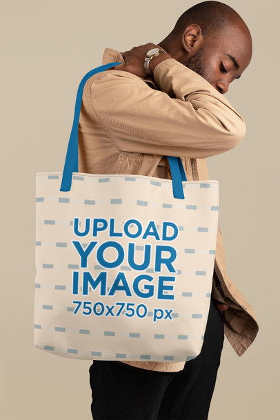 Mockup of a Young Man Carrying a Tote Bag with Customizable Strap at a Studio