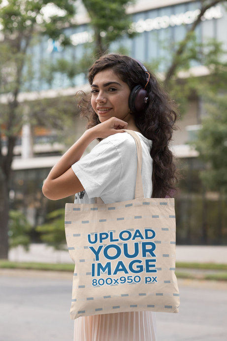 Tote Bag Mockup of a Woman with Headphones in the City