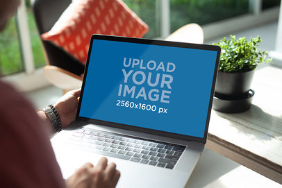 Mockup of a Man Using a MacBook Pro at Home