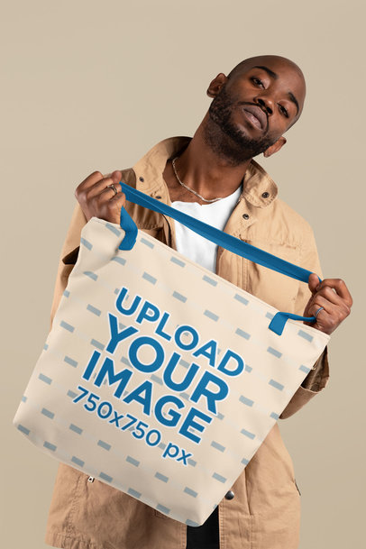 Mockup of a Bald Man Holding a Tote Bag with Customizable Strap at a Studio