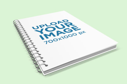 Mockup of a Spiral Notebook Lying on a Solid Color Surface 