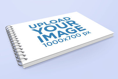 Mockup of a Spiral Notebook Lying on a Plain Color Surface