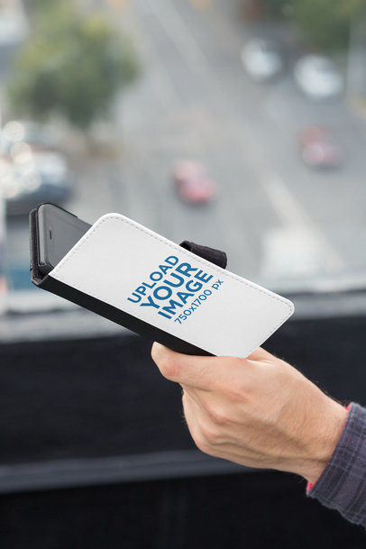 Mockup of a Man's Hand Holding a Wallet Case for iPhone X at a Balcony 29822