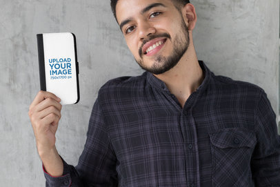 Mockup of a Man Holding an iPhone 8 Plus Wallet Case Against a Concrete Wall 29828