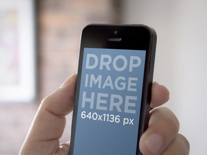 Mockup of a Hand Holding an iPhone 5 Black in Portrait Position 