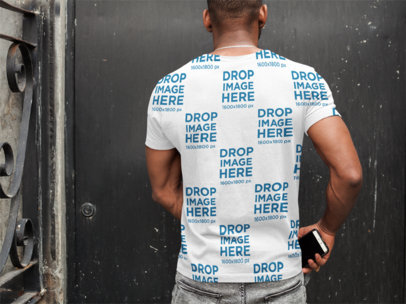 Back of a Man Wearing a T-Shirt Mockup while Facing a Wall