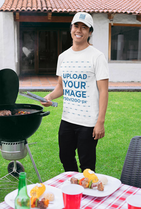 T-Shirt Mockup of a Man with a Dad Hat Grilling at a BBQ Party