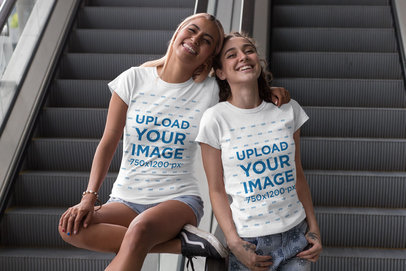 Mockup of Two Friends with Matching T-Shirts Posing By an Escalator 
