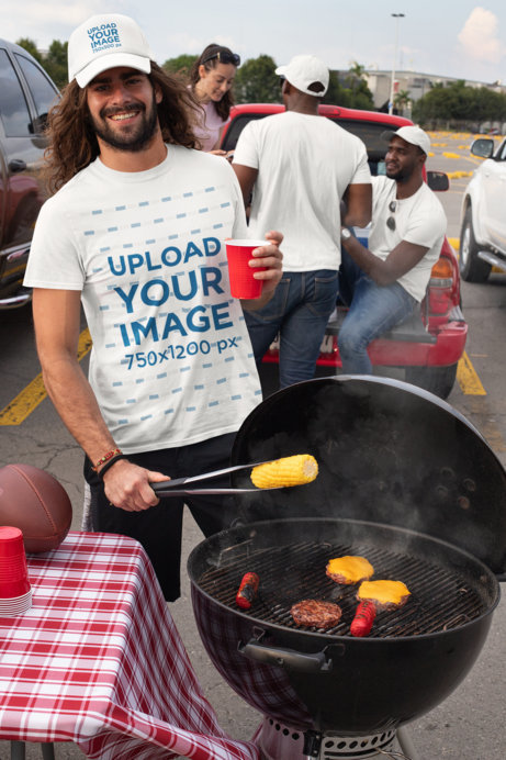 T-Shirt Mockup of a Smiling Man Wearing a Trucker Hat at a Tailgate Party