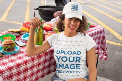 T-Shirt Mockup of a Curly-Haired Woman With a Trucker Hat at a Tailgate Party 