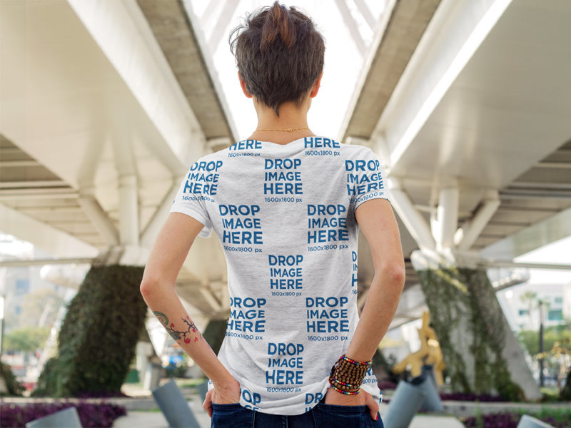 Back of a Woman Wearing a Sumbilated Tee Mockup under a Bridge