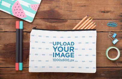 Mockup of a Pouch Laying on a Wooden Surface with Stationery Tools