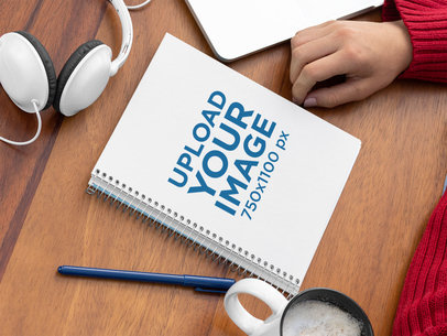 Spiral Notebook Mockup Placed over a Wooden Surface by Some Headphones