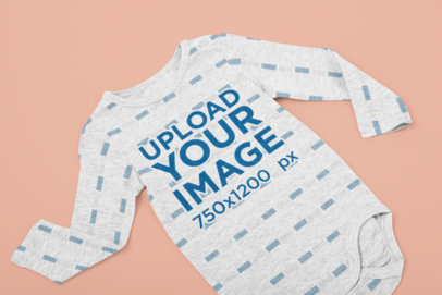 Mockup of a Heathered Long-Sleeve Onesie on a Flat Surface