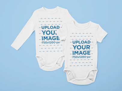 Flat Lay Mockup of Two Onesies on a Solid Surface