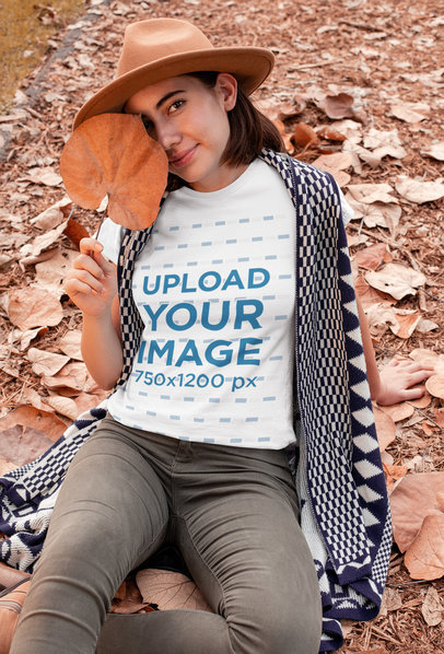 T-Shirt Mockup of a Woman Sitting on a Field with Fall Leaves 