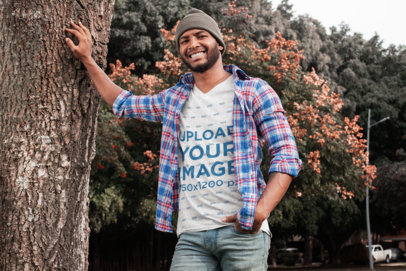V-Neck T-Shirt Mockup Featuring a Man Leaning on a Tree