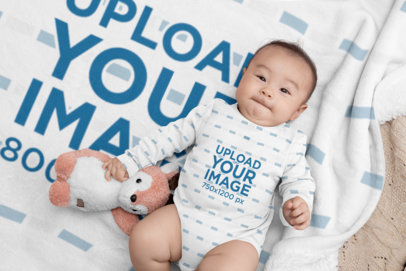Mockup of a Baby Wearing a Onesie Lying on a Fleece Blanket 