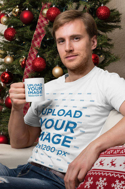 T-Shirt Mockup of a Man Holding an 11 oz Mug Sitting in Front of a Christmas Tree