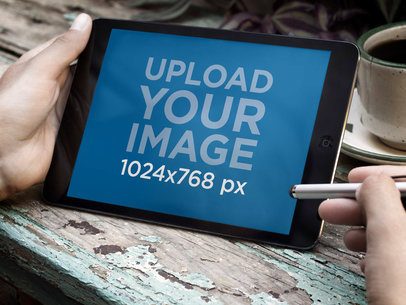 Mockup of a Man Using an iPad Mini in a Café