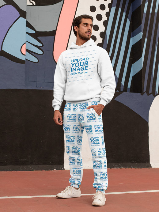 Hoodie Mockup of a Bearded Man Wearing Sweatpants Against a Graffiti Wall 