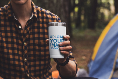 Mockup of a Man Holding a Travel Mug at a Campsite 