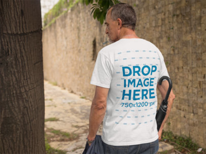 Back of an Elder Man Wearing a T-Shirt Mockup Carrying an Umbrella