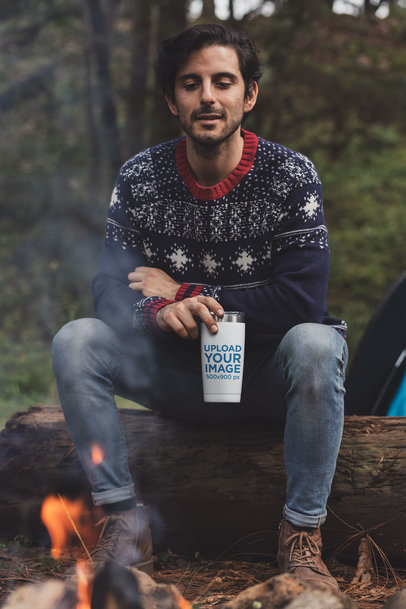 Mockup of a Man at a Campfire Drinking from a Tumbler 