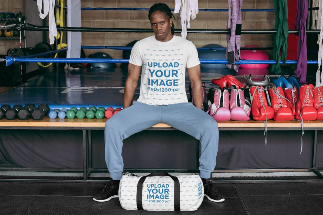 T-Shirt Mockup of a Tough-Looking Man with a Duffle Bag at a Boxing Gym