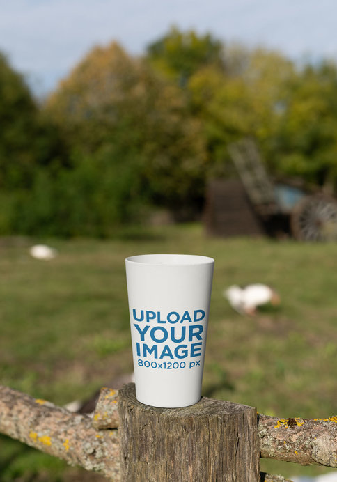 Placeit - Mockup of a Reusable Cup Placed on a Wooden Fence