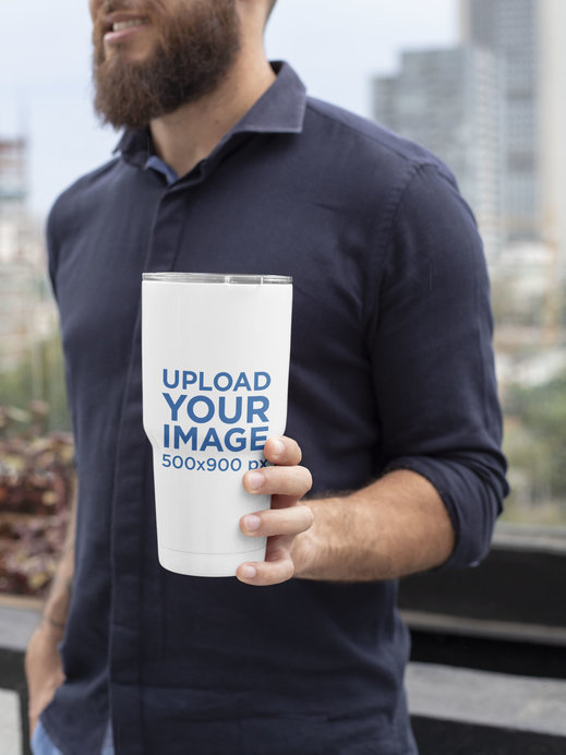 Mockup of a Bearded Man Holding a 30 oz Travel Mug in the City