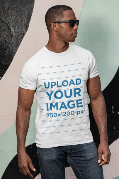 Mockup of a Man with Sunglasses Wearing a Customizable T-Shirt Against a Painted Wall 