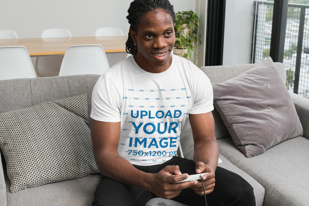 T-Shirt Mockup Featuring a Man Holding a Wired Gaming Controller