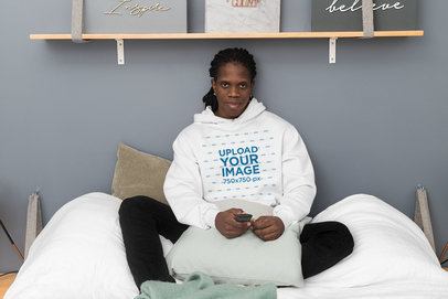 Pullover Hoodie Mockup Featuring a Man Sitting on His Bed 