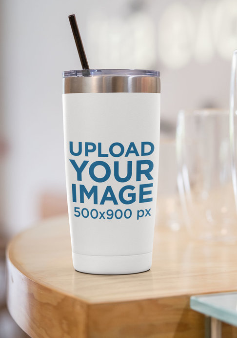 Mockup of a 20 oz Travel Mug Placed by a Glass