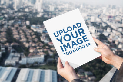 Mockup of a Man Holding a Magazine Against a City Landscape 