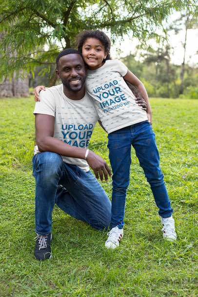 Mockup of a Dad and His Daughter Wearing Customizable T-Shirts in the Park