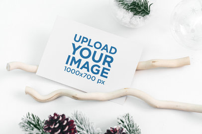 Mockup of a Christmas Card Placed over a White Surface by Some Winter Decorations 