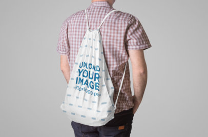 Mockup of a Man Carrying a Drawstring Back on His Back