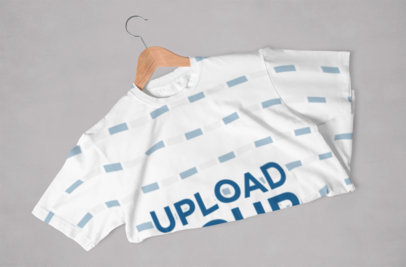 Mockup Featuring a Folded Sublimated T-Shirt Placed Over a Solid Color Surface 