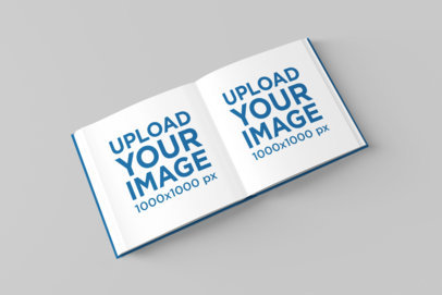 Mockup of a Square Hardcover Book Lying Open on a Solid Color Surface 1548-el