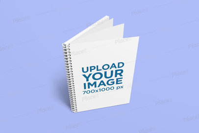 Mockup Featuring a Spiral Notebook Standing on a Plain Color Surface 