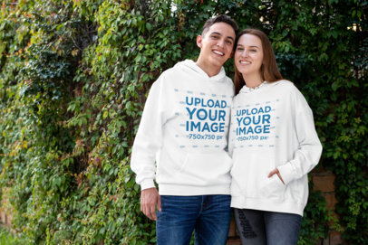 Pullover Hoodie Mockup of a Smiling Couple Against a Vertical Garden