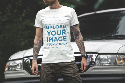T-Shirt Mockup Featuring a Tattooed Man Standing in Front of a Truck 