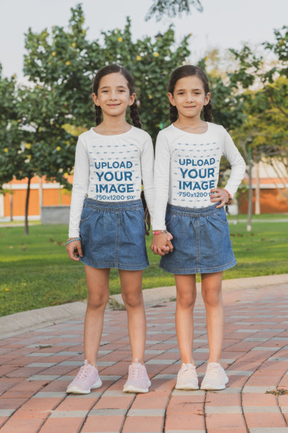 Mockup of Two Sisters With Long Sleeve Tees Holding Hands at a Park 